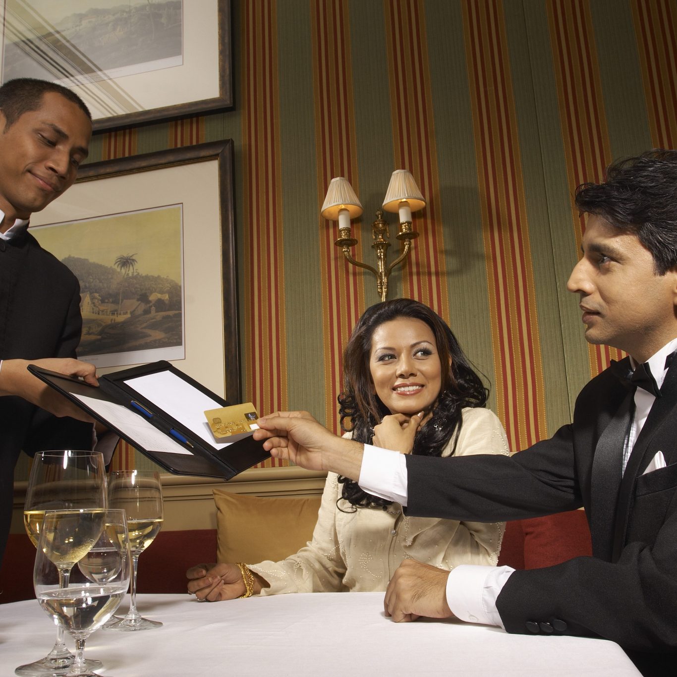 Man handing credit card to waiter in upscale restaurant