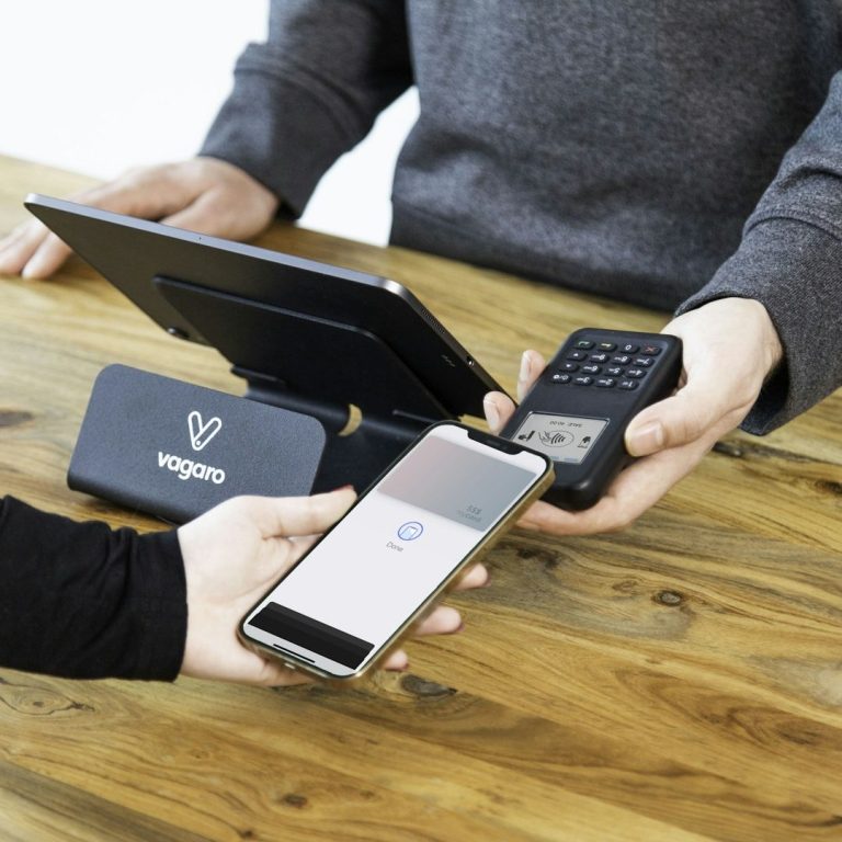 Woman using a mobile phone for contactless payment on a countertop terminal