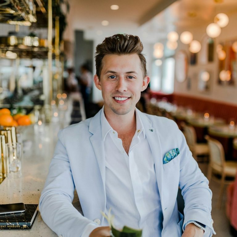 Smiling man in a white blazer giving a testimonial at a modern café